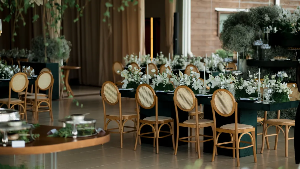 Réception de mariage en intérieur joliment décorée avec compositions florales et sièges élégants