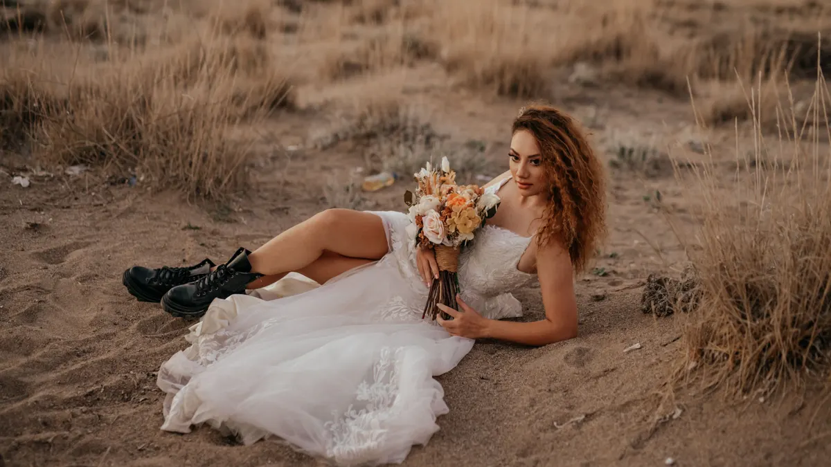 Mariée avec un bouquet de fleurs allongée sur le sol