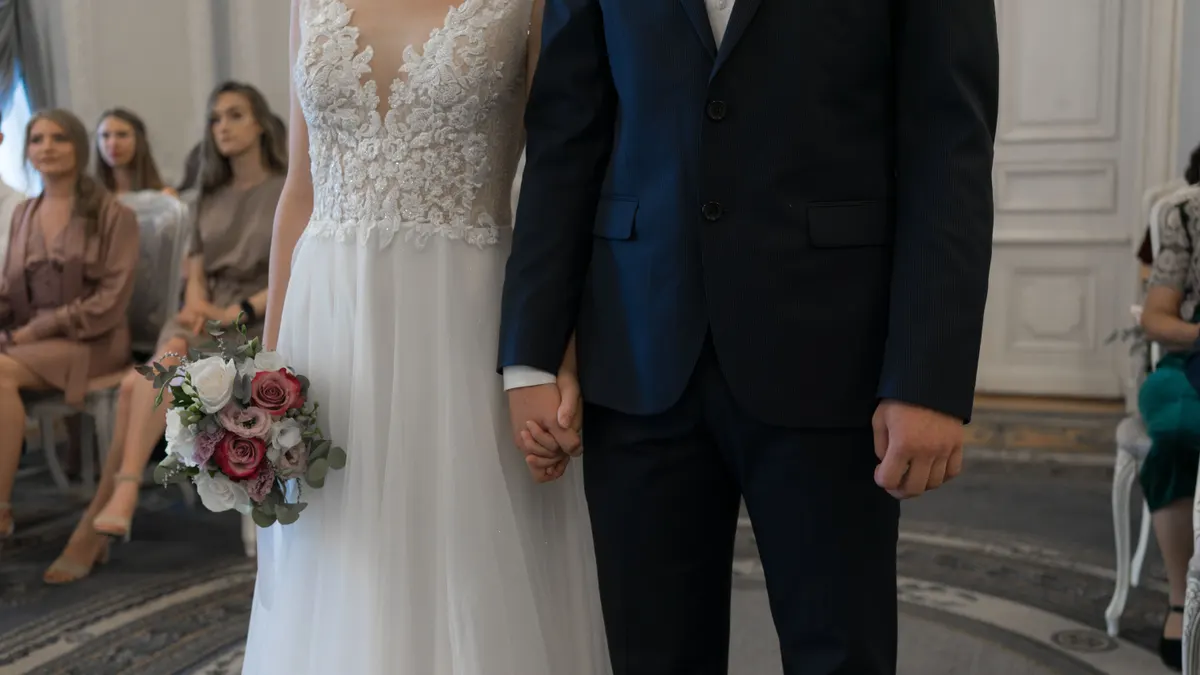 Mariée et marié se tenant la main pendant une cérémonie de mariage en intérieur